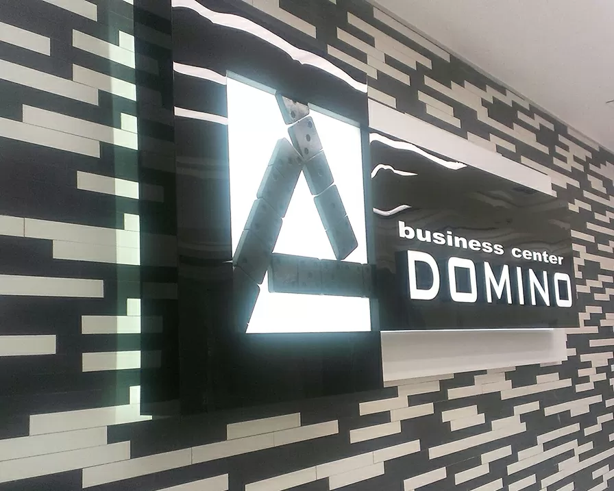 Світлова вивіска DOMINO на фасаді будівлі вечірня підсвітка
